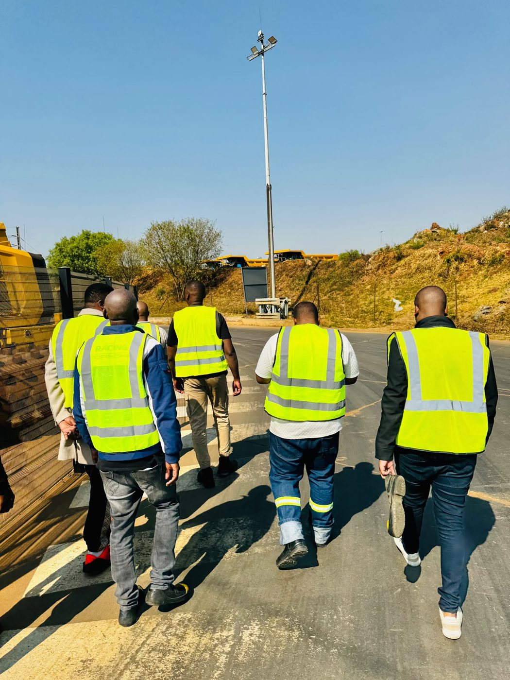 SVT Group team in reflective vests walking on a haul road with mining plant in the background